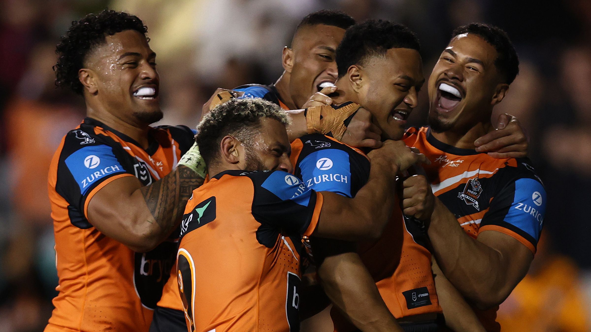 Latu Fainu of the Wests Tigers celebrates with teammates after scoring a try.